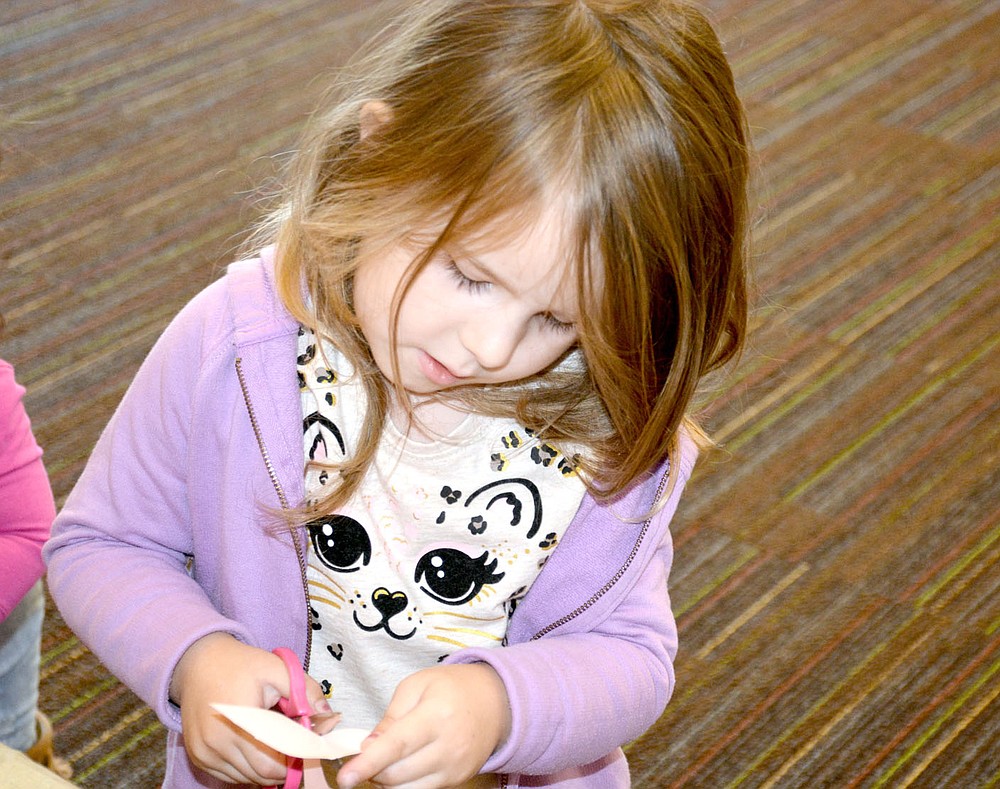 Marc Hayot/Siloam Sunday Reylla Welch, 5, cuts out a piece for the scarecrow she is making at the Siloam Springs Public Library's homeschooling program. This free program is held weekly at 11 a.m. on Thursdays.