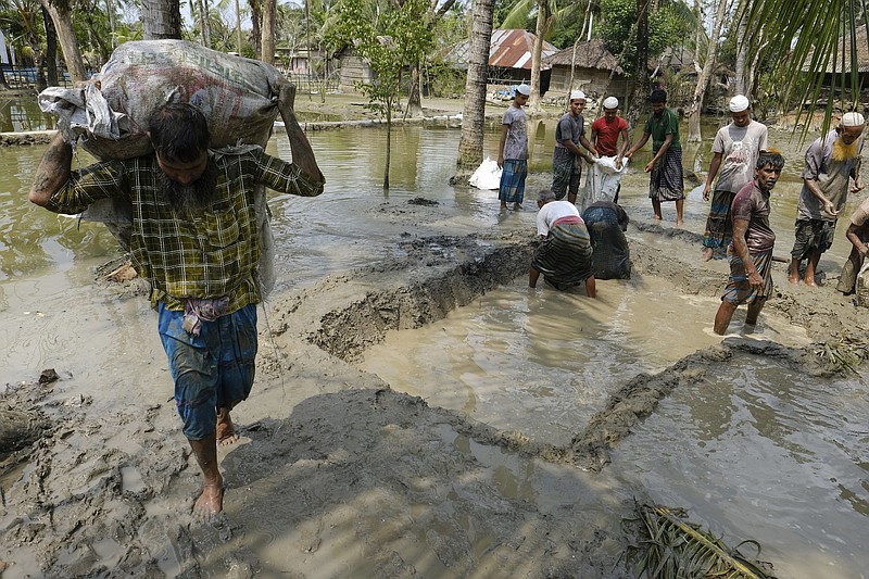 Villagers make a dam with mud in plastic bags to protect their only road in Pratap Nagar, that lies in the Shyamnagar region, in Satkhira, Bangladesh on Oct. 5, 2021. In 1973,  0.833 million hectares were affected by the encroaching seawater, accelerated by more frequent cyclones and higher tides, that has contaminated water supplies.  That's bigger than the U.S. state of Delaware. That increased to 1.02 million hectares in 2000, and to 1.056 million hectares in 2009, according to Bangladesh&#x2019;s Soil Resources Development Institute. Salinity in soil has increased by 26% over the past 35 years, and continues to do so every year. Officials working in the Shyamnagar region admit that paucity of funds was preventing the government from building new desalination plants that would convert saltwater to fresh water. (AP Photo/Mahmud Hossain Opu)