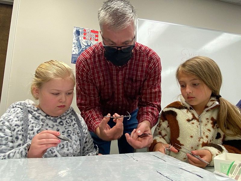 Dr. Paul Jenkins, center, a veterinarian from Vilonia, teaches Haven Register of Conway and Ava Beene of Vilonia how to suture. The practice was part of a 4-H Vet Camp held recently. (Special to The Commercial/Tracy Courage, University of Arkansas System Division of Agriculture)