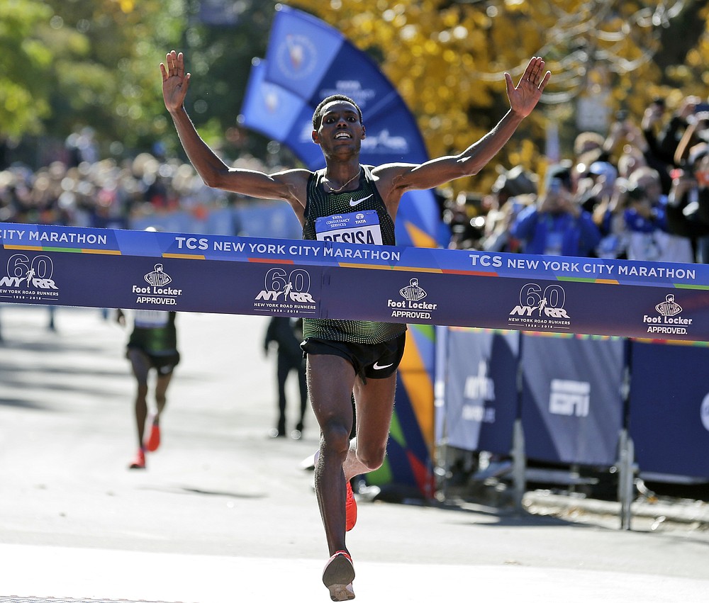 FILE - Lelisa Desisa, of Ethiopia, crosses the finish line first in the men's division of the New York City Marathon, Nov. 4, 2018. A limited field of 33,000 runners will jog off the Verrazzano Bridge and wind its way toward Central Park on Sunday as the New York City Marathon returns for its 50th edition after being wiped out in 2020 by the coronavirus pandemic. (AP Photo/Seth Wenig, File)
