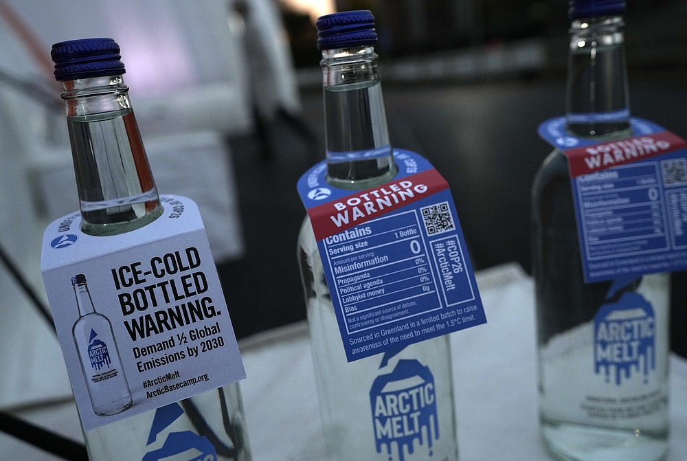 Bottles containing melted ice water on display close to where an iceberg delivered by members of Arctic Basecamp was placed on show near the COP26 U.N. Climate Summit in Glasgow, Scotland, Friday, Nov. 5, 2021. The four ton block of ice, originally part of a larger glacier, was brought from Greenland to Glasgow by climate scientists from Arctic Basecamp as a statement to world leaders of the scale of the climate crisis and a visible reminder of what Arctic warming means for the planet. (AP Photo/Alastair Grant)