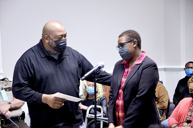 Justice of the Peace Reginald Adams presents Marcie Johnson with a covid-19 survivor's benefit. Johnson's husband died who was also Adams' cousin.