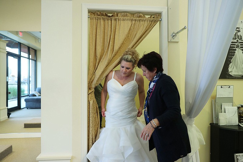 Amy Barmann exits a changing room in her wedding dress with help from bridal tailor Venera Lazova at Eva's Bridal International on Nov. 4, 2021, in Orland Park. Barmann had to delay her wedding from November 2020 to later this month because of the COVID-19 pandemic. (John J. Kim/Chicago Tribune/TNS)