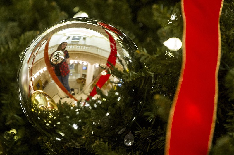 Sara Kunau hangs ornaments on a Christmas tree in the rotunda of the Arkansas State Capitol on Tuesday, Nov. 9, 2021. (Arkansas Democrat-Gazette/Stephen Swofford)