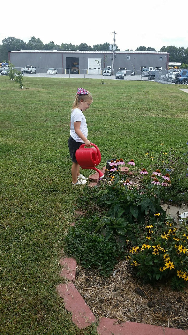 PHOTO PROVIDED BY KEN SCHUTTEN. Primary student is shown watering flowers in the new school garden. Students from early education to second grade work in the garden.