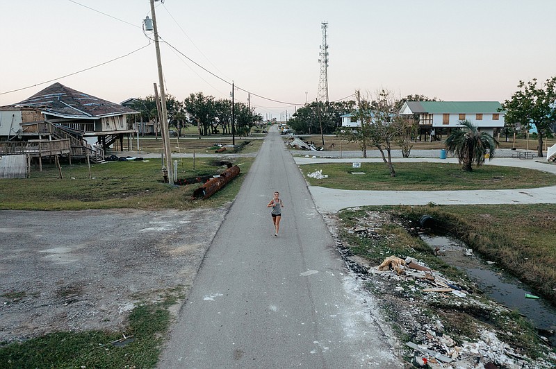 Londyn Resweber, 14, a member of the Grand Isle School cross-country team, runs down a street in Grand Isle, La., on Oct. 25. Hurricane Ida knocked down much of Grand Isle, but the town’s cross-country team was determined to compete in the state championship meet, which was held Monday. (The New York Times/Bryan Tarnowski)