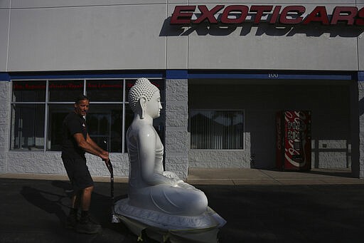 Dave Ley, co-owner of Exoticars, an auto restoration shop specializing in classic vehicles, pulls a newly restored statue of the Buddha outside in McCandless, Pa., on Monday, Oct. 11, 2021. Workers repainted and repaired the figure for the Pittsburgh Buddhist Center, which brought it from Sri Lanka over 15 years ago. (AP Photo/Jessie Wardarski)