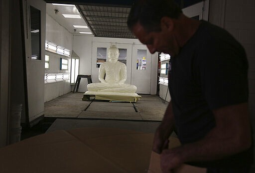 Dave Ley, co-owner of Exoticars, an auto restoration shop specializing in classic vehicles, cuts out a template for the new base of large statue of the Buddha in McCandless, Pa., on Monday, Oct. 11, 2021. After weeks of restoration, the statue, originally manufactured in Sri Lanka, was unveiled at the Pittsburgh Buddhist Center on Oct. 24. (AP Photo/Jessie Wardarski)