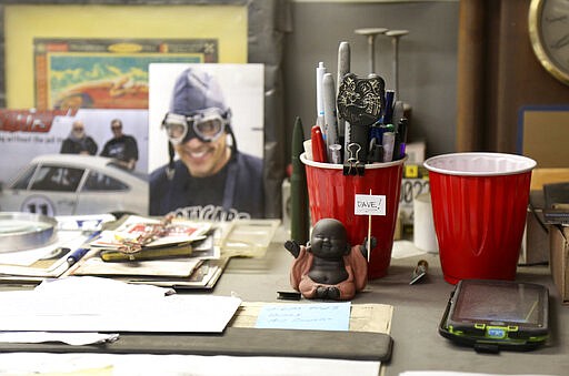 A figurine of the Buddha sits on the desk of Dave Ley, co-owner of Exoticars, an auto restoration shop specializing in classic vehicles, in McCandless, Pa., on Monday, Oct. 11, 2021. The shop recently restored a larger statue of the Buddha for the Pittsburgh Buddhist Center, where it was unveiled Oct. 24. (AP Photo/Jessie Wardarski)