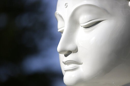 A newly restored statue of the Buddha shines in the sunlight outside Exoticars, an auto restoration shop specializing in classic vehicles, in McCandless, Pa., on Monday, Oct. 11, 2021. Workers stripped multiple coats of deteriorating paint and primer from the 15-year-old statue and repainted it, a process that took weeks. They also repaired cracks in the fiberglass and added a metal strip to strengthen the base. The refurbished statue, originally manufactured in Sri Lanka, was unveiled at the Pittsburgh Buddhist Center on Oct. 24. (AP Photo/Jessie Wardarski)
