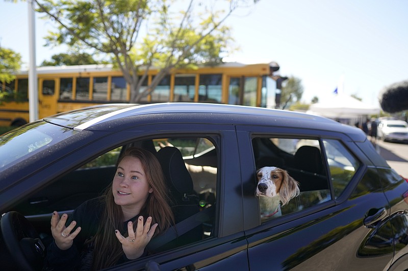 Brooklyn Pittman talks as she sits in her car with her dogs after receiving food from an Armed Services YMCA food distribution, Oct. 28, 2021, in San Diego. As many of 160,000 active duty military members are having trouble feeding their families, according to Feeding America, which coordinates the work of more than 200 food banks around the country. (AP Photo/Gregory Bull)