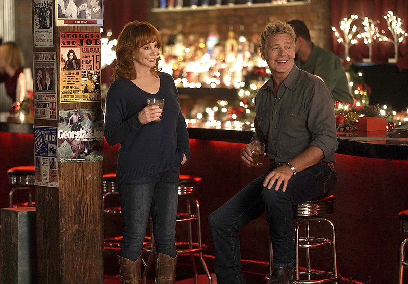 Reba McEntire (left) and John Schneider appear in the holiday special “Reba McEntire’s Christmas in Tune,” premiering Nov. 26 on Lifetime. (Lifetime via AP)