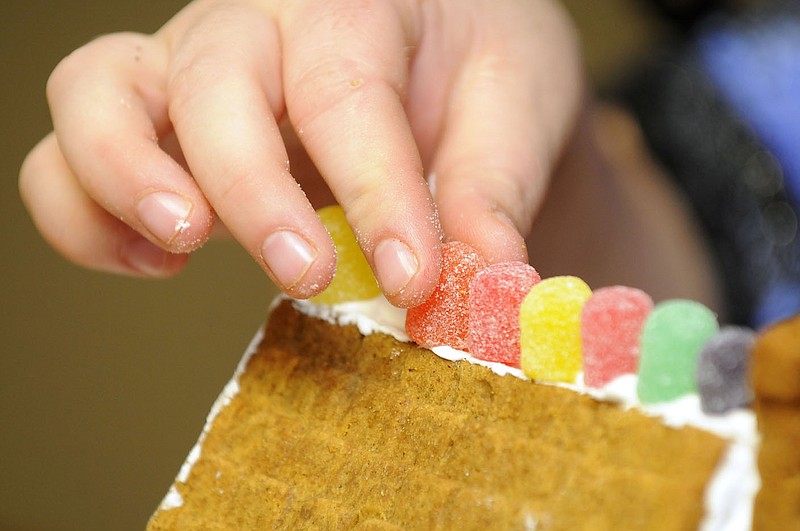 STAFF PHOTO J.S. WEDGEWORTH
Evelyn Collins, a resident at Saving Grace in Rogers, places a gum drop on the roof while building a ginger bread house on Sunday, Dec. 4, 2011. The house building activity is part of Saving Grace's Weekend Warrior program that has volunteers work with the residents on a project or craft during the weekend.