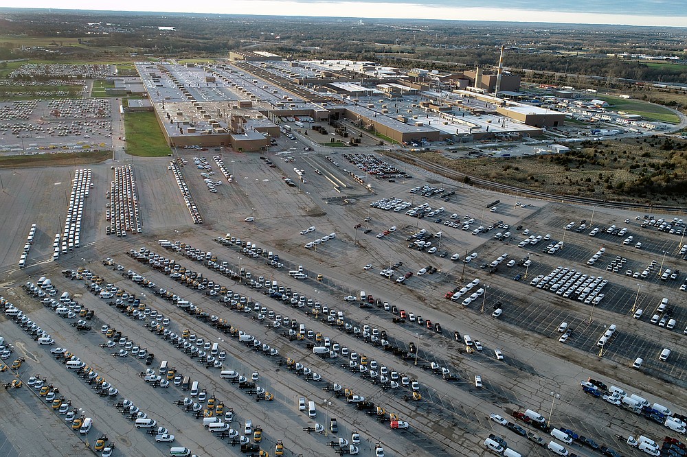 FILE - In this aerial photo, a General Motors assembly plant is seen at top right while mid-sized pickup trucks and full-size vans currently produced at the plant are seen in a parking lot outside Wednesday, March 24, 2021, in Wentzville, Mo. Experts say unless more spending shifts back to services or something else motivates people to stop buying, it could take well into next year or even 2023 before the U.S. and global supply chains return to some semblance of normal. (AP Photo/Jeff Roberson, File)