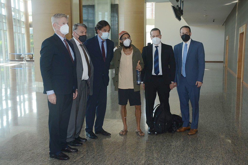 In this photo provided by the Myanmar Military True News Information Team, released American journalist Danny Fester, centre, poses next to former U.S. Ambassador to the U.N. Bill Richardson, third from left and members of his team at the Naypyitaw Airport in Naypyitaw, Myanmar, Monday, Nov. 15, 2021. Fenster, who was recently sentenced to 11 years of hard labor after spending nearly six months in jail in military-ruled Myanmar, has been freed. A former U.S. diplomat who helped negotiate the release said Fenster was on his way home Monday. (Myanmar Military True News Information Team via AP)