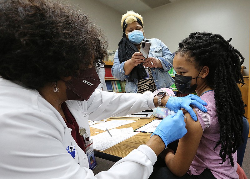 Amari Denay Hunter, 9, gets her covid-19 vaccine shot from school nurse, Rachel White (left), as her mother, Wanda Hunter (center), takes a photo during the vaccine clinic on Monday, Nov. 15, 2021, at Stephens Elementary School in Little Rock. (Arkansas Democrat-Gazette/Thomas Metthe)