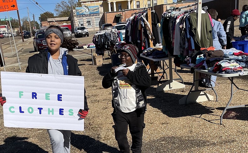 Nadia Turner is holding up her sign and Dominic Wise is ready to give out important church literature as the two invite the public to a free clothing event in Linden on Saturday. The two were helping with a project by the Pleasant Hill Missionary Baptist Church.