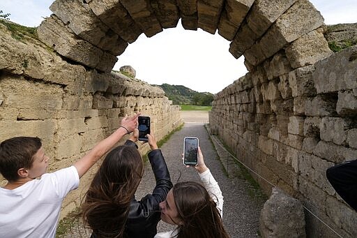 School students use a mobile app at the ancient site of Olympia, southwestern Greece, Wednesday, Nov. 10, 2021. Microsoft launched a digital restoration project at the ancient birthplace of the Olympic Games in southern Greece Wednesday to provide visitors an immersive recreation of temples and competition areas as they walk through the ruins. (AP Photo/Thanassis Stavrakis)