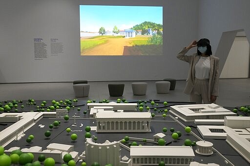 Museum supervisor Xenia Vlahou uses mixed-reality HoloLens headset as she stands in front of a scale model of Ancient Olympia at the Olympic Museum in Athens, Greece, Tuesday, Nov. 9, 2021. The installation is part of a digital restoration project by Microsoft and the Greek Ministry of Culture and Sport at Ancient Olympia, birthplace of the Olympic Games. (AP Photo/Thanassis Stavrakis)