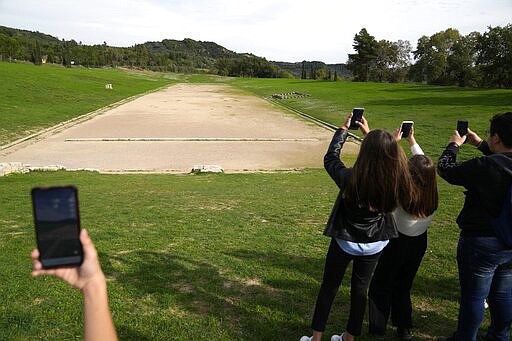 School students use a mobile app at the ancient site of Olympia, southwestern Greece, Wednesday, Nov. 10, 2021. Microsoft launched a digital restoration project at the ancient birthplace of the Olympic Games in southern Greece Wednesday to provide visitors an immersive recreation of temples and competition areas as they walk through the ruins. (AP Photo/Thanassis Stavrakis)