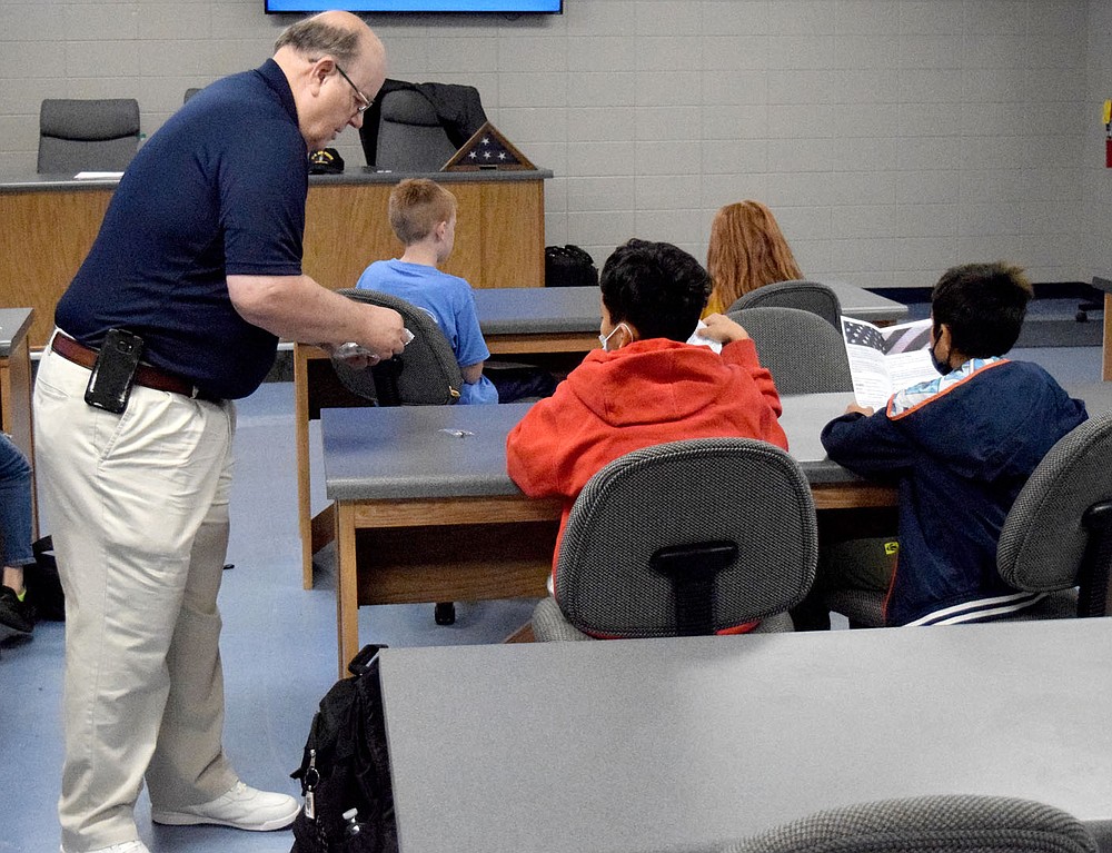 Westside Eagle Observer/MIKE ECKELS
Alan G. Nabb, Lt. Col, Retired, hands two fifth grade students an American Flag pin during his class on the American Flag Nov. 16 in the media room at Decatur Middle School. Nabb was in Decatur to teach the history and proper flag etiquette to the young students at the middle school.