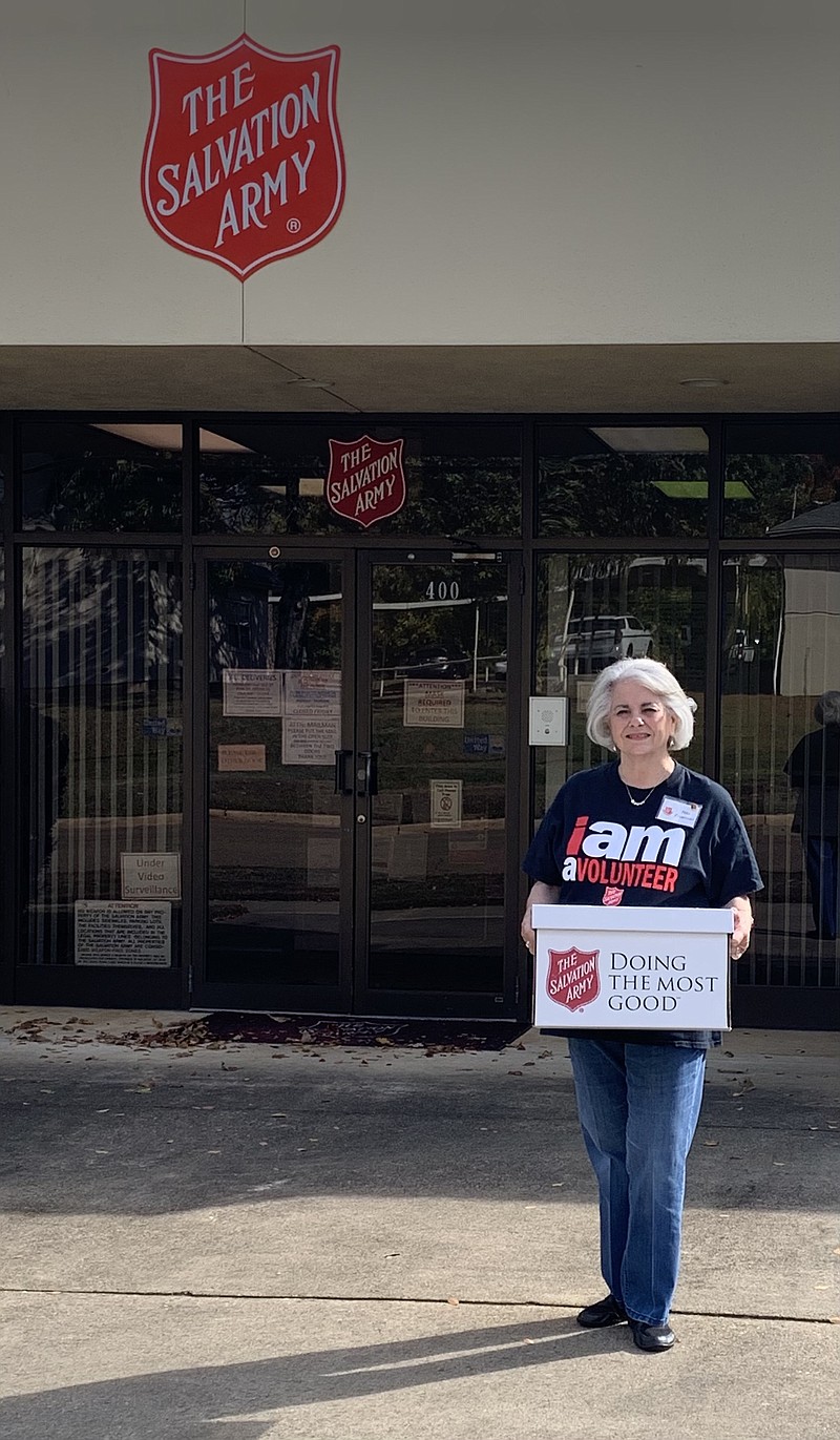 Rita Freeman poses with a food box in front of the Texarkana Salvation Army Corp. Freeman has been a member of the Women’s Auxiliary for about 11 years and volunteers in the pantry.