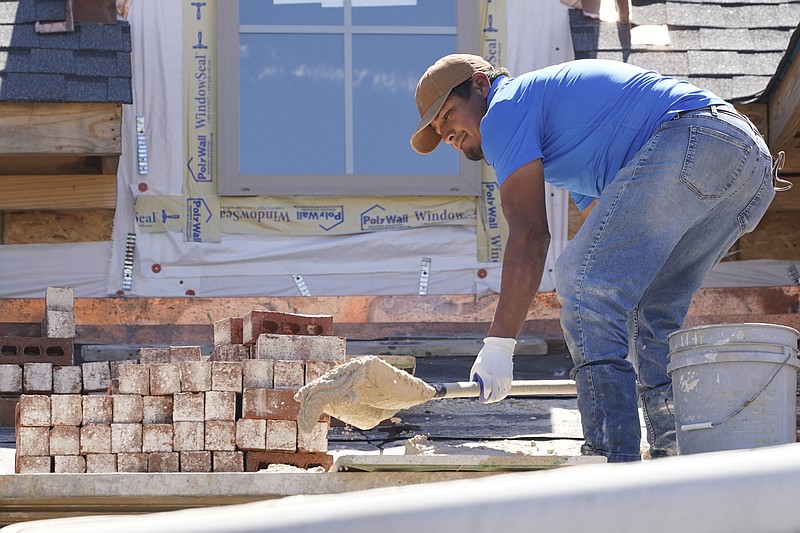 FILE - A mason shovels a cement mixture as he prepares to lay down bricks on the exterior wall of a new house in Flowood, Miss., Sept. 23, 2021. U.S. home construction fell 1.6% in September as builders continue to be tripped up by supply chain bottlenecks. The Commerce Department reported Tuesday, Oct. 19, 2021 that the decline in September left home construction at a seasonally adjusted annual rate of 1.56 million units, 7.4% above the rate one year ago. (AP Photo/Rogelio V. Solis, file)