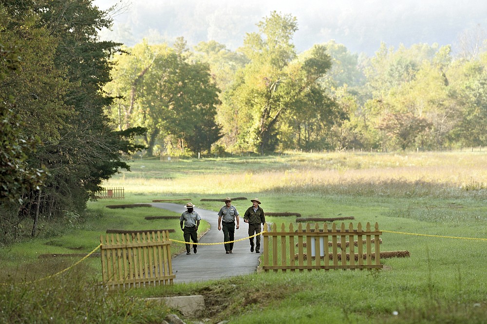 FILE - From left, Great Smoky Mountains National Park Superintendent Cassius Cash, Deputy Superintendent Alan Sumeriski, and National Park Service Roads and Trails Branch Supervisor Tobias Miller walk on the newly improved trail to the John Oliver Cabin, Sept. 28, 2021, in Great Smoky Mountains National Park, Tennessee. Americans may soon get a better glimpse into a future of green-friendly transportation by visiting a U.S. national park. It’s a joint pledge being signed Wednesday by Interior Secretary Deb Haaland and Transportation Secretary Pete Buttigieg to test some of the newest and most innovative travel technologies on public lands. The plan is being made possible by the $1 trillion infrastructure law and other federal spending. Under new pilot programs, visitors to national parks could see self-driving shuttle buses, along with more electric scooter or bike stations and electric charging stations for travelers in zero-emission cars. Yellowstone National Park would see some of the most immediate updates, with other sites to follow. (Scott Keller/The Daily Times via AP, file)