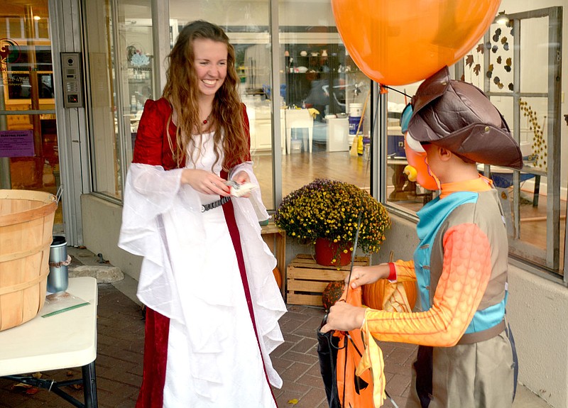 Marc Hayot/Herald-Leader Eryn Ausherman, the owner of Broken Vessels hands out candy to a trick or treater during the downtown trick or treating event held on Oct. 29.