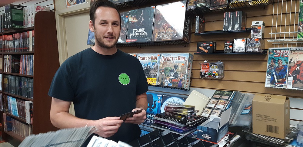 Chase Fairless, Retail Manager at Excalibur Comics & Games, organizes the Magic The Gathering cards while chatting with customers.  As a local business that has served Texarkana for almost 35 years, Excalibur and the fans who shop there form an established community that loves what they do.