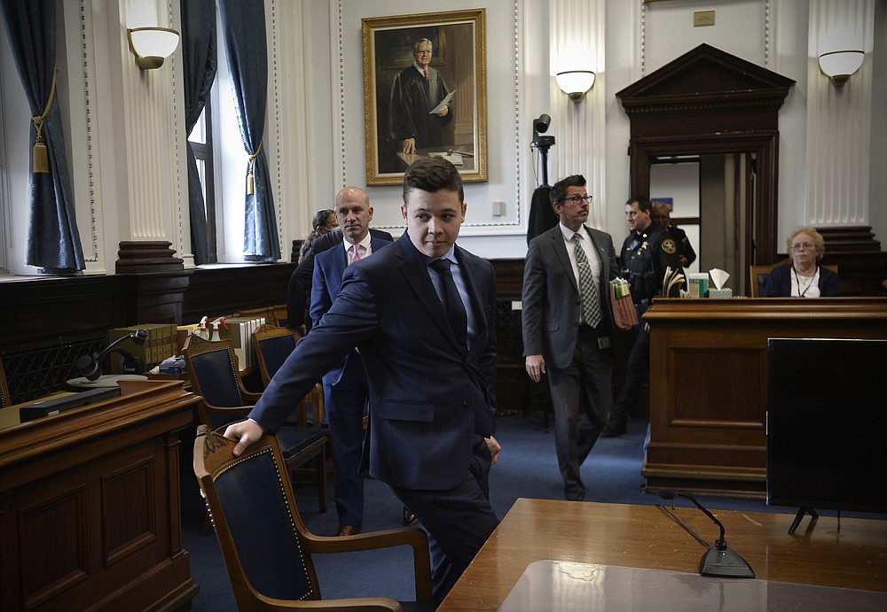 Kyle Rittenhouse, center, pulls out his chair for a meeting Judge Bruce Schroeder called during his trial at the Kenosha County Courthouse in Kenosha, Wis., on Thursday, Nov. 18, 2021. (Sean Krajacic/The Kenosha News via AP, Pool)
