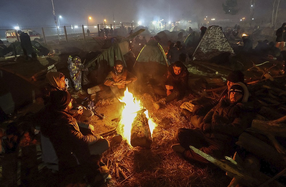 Migrants warm themselves near a fire as they gather at the checkpoint "Kuznitsa" at the Belarus-Poland border near Grodno, Belarus, on Wednesday, Nov. 17, 2021. Some of the migrants have children with them at the border in their desperate bid to reach the EU. Most are fleeing conflict, poverty and instability in the Middle East and elsewhere. (Maxim Guchek/BelTA via AP)