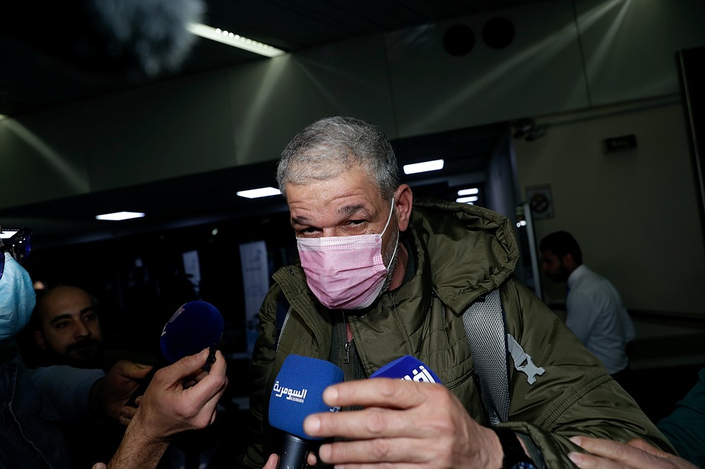 Abdul Sattar balm, center, an Iraqi migrant arrives to the airport in Baghdad, Iraq, Thursday, Nov. 18, 2021.Hundreds of Iraqis have returned home from Belarus after abandoning their hopes of reaching the European Union in a repatriation that follows more than a week of tensions at Poland's eastern border, where thousands of migrants were stuck in a cold and soggy forest. (AP Photo/Khalid Mohammed)