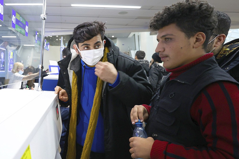 Migrants from Iraq talk to each others they lineup to be registered on a special flight to Iraq at the National Airport outside Minsk, Belarus, Thursday, Nov. 18, 2021. A plane carrying migrants back to Iraq is due to leave the Belarusian capital Minsk on Thursday, part of efforts by the Iraqi authorities to help citizens to have been stranded at the border between Belarus and Poland in the hope of getting into the European Union. Spokesman of the Iraqi Foreign Minister Ahmed Al Sahhaf said Thursday that at least 430 people have registered to return to Iraq from Belarus, and the authorities were in process of registering 50 more. (Andrey Pokumeiko/BelTA via AP)