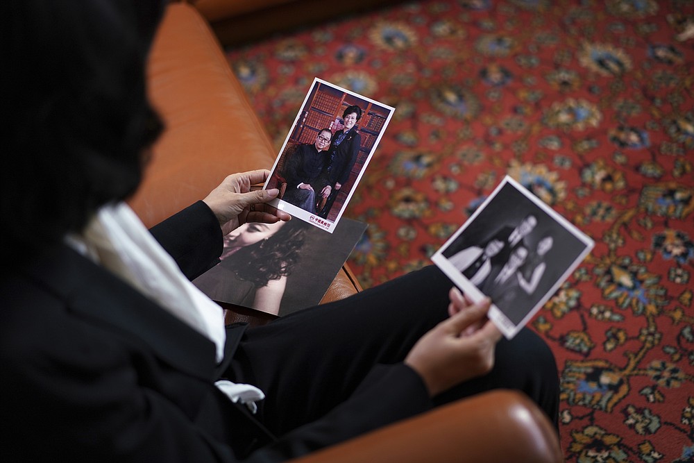 Grace Meng, the wife of former Interpol president Meng Hongwei, shows photos of her parents as she answers the Associated Press in Lyon, central France, Tuesday, Nov.16, 2021. In the exclusive interview, Meng chose to show her face for the first time since her husband disappeared in China in 2018, agreeing to be filmed and photographed without the dark lighting and from-the-back camera angles that she had previously insisted on. She did so to be able to speak openly and in unprecedented detail about her husband's imprisonment, herself and the cataclysm that tore them apart. (AP Photo/Laurent Cipriani)