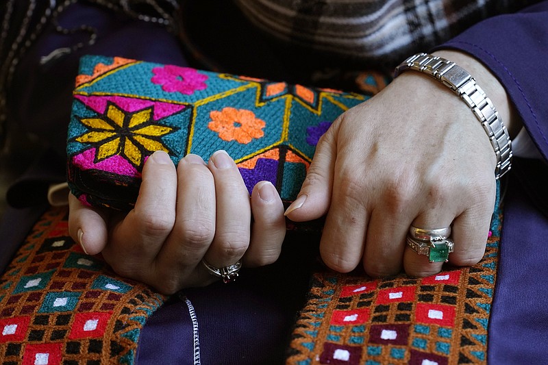 A Massachusetts resident identifying herself only as &quot;Safi,&quot; who asked that her last name not be used for fear of retribution against her relatives in Afghanistan, holds a purse with traditional Afghan patterns, Tuesday, Nov. 9, 2021, during an interview with The Associated Press. Thousands of Afghans have applied for temporary admission into the U.S. for humanitarian reasons, but few have been approved since the Taliban recaptured control of their homeland. &quot;We're worried for their lives,&quot; said Safi, whose family is sponsoring some 20 other relatives seeking humanitarian parole. (AP Photo/Steven Senne)