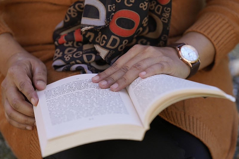 An Afghan woman identifying herself only as Bahara, who lives in Massachusetts, and asked her last name be withheld over concerns for her family, holds a book Tuesday, Nov. 9, 2021, during an interview with The Associated Press. The 29-year-old boarded a plane Aug. 15, 2021, just hours before the Taliban swept into the capital of Kabul, leading to one of the largest mass evacuations in U.S. history. Thousands of Afghans have applied for temporary admission into the U.S. for humanitarian reasons, but few have been approved since the Taliban recaptured control of their homeland. (AP Photo/Steven Senne)