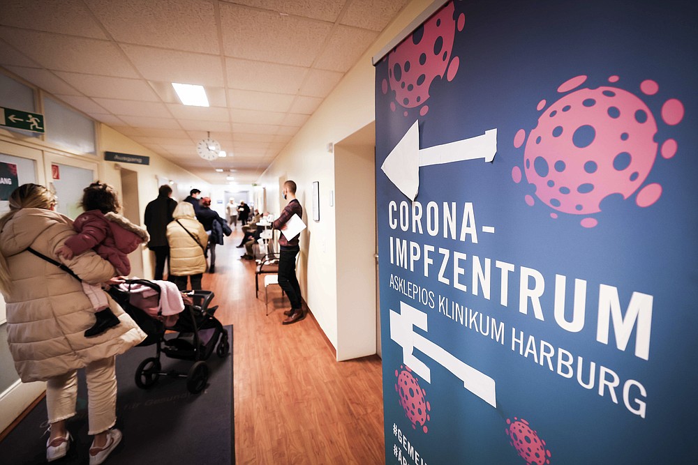 Numerous people wait in a corridor at the Corona vaccination centre at the Asklepios Klinikum Harburg, Germany, Friday, Nov.19, 2021 In view of the rapidly increasing Corona numbers, Hamburg also relies on booster vaccinations, the demand for the booster vaccinations is increasing. (Christian Charisius/dpa via AP)