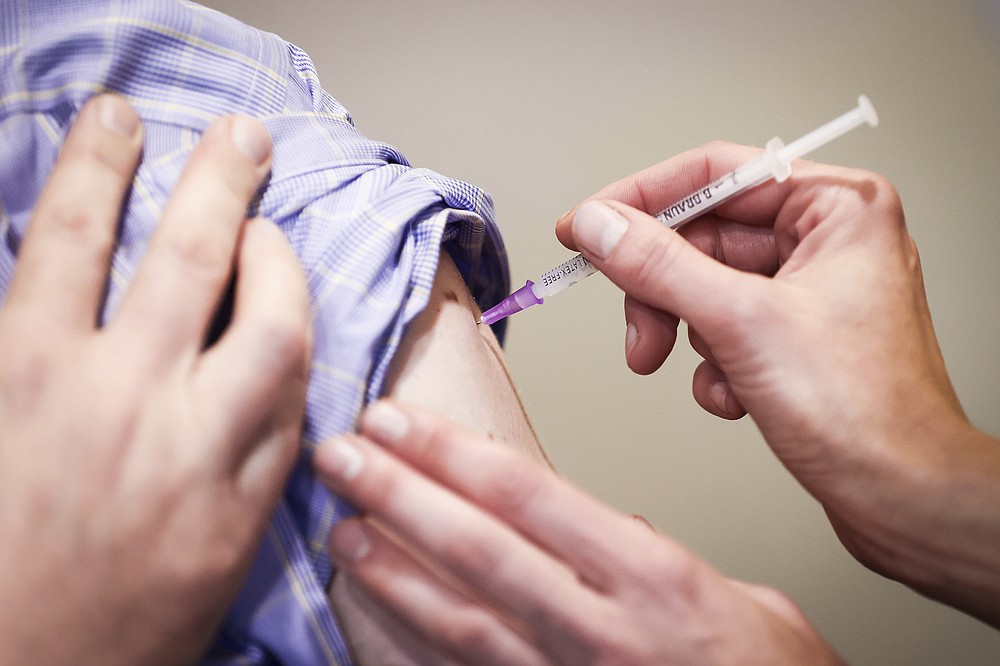A man gets his booster vaccination at the Corona Vaccination Center at the Asklepios Klinikum Harburg, Germany, Friday, Nov.19, 2021. In view of the rapidly increasing Corona numbers, Hamburg also relies on booster vaccinations, the demand for the booster vaccinations is increasing. (Christian Charisius/dpa via AP)