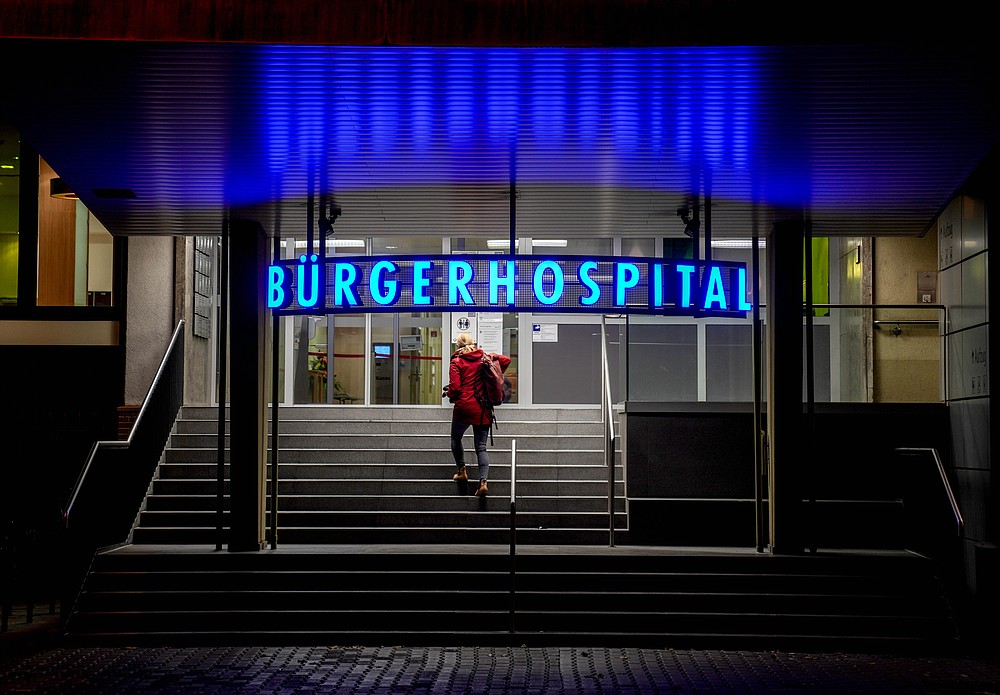 A woman walks up the stairs of a hospital in Frankfurt, Friday, Nov. 19, 2021. The government announced that the hospitalization rate will decide about further restrictions to avoid the outspread of the coronavirus. (AP Photo/Michael Probst)