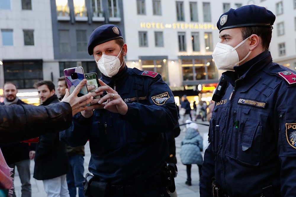 Police officers check the vaccination status of visitors during a patrol on a Christmas market in Vienna, Austria, Friday, Nov. 19, 2021. Austrian Chancellor Alexander Schallenberg says the country will go into a national lockdown to contain a fourth wave of coronavirus cases. Schallenberg said the lockdown will start Monday, Nov.22, and initially last for 10 days. (AP Photo/Lisa Leutner)