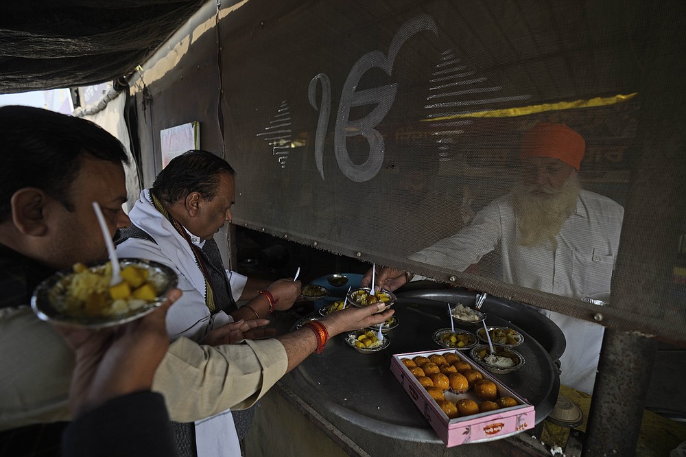 Farmers distribute sweets to celebrate news of the repeal of farm laws they were protesting against, in Singhu, on the outskirts of New Delhi, India, Friday, Nov. 19, 2021. In a surprise announcement, India&#x27;s Prime Minister Narendra Modi said Friday his government will withdraw the controversial agriculture laws that prompted yearlong protests from tens of thousands of farmers and posed a significant political challenge to his administration. (AP Photo/Manish Swarup)