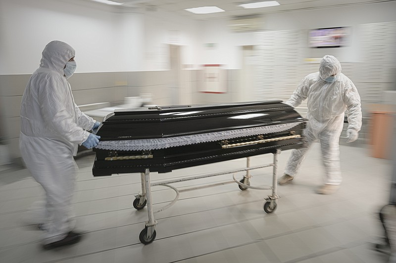 FILE - Funeral house employees drag a coffin on a trolley as they arrive at the University Emergency Hospital morgue to take a COVID-19 victim for burial, in Bucharest, Romania, Monday, Nov. 8, 2021. This was supposed to be the Christmas in Europe where family and friends could once again embrace holiday festivities and one another. Instead, the continent is the global epicenter of the COVID-19 pandemic as cases soar to record levels in many countries. With infections spiking again despite nearly two years of restrictions, the health crisis increasingly is pitting citizen against citizen &#x2014; the vaccinated against the unvaccinated. (AP Photo/Vadim Ghirda, File)