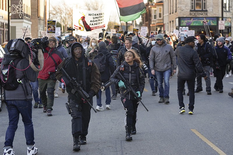 Erick Jordan and his daughter Jade, 16, carry rifles ahead of protesters marching, Sunday, Nov. 21, 2021, in Kenosha, Wis. Kyle Rittenhouse was acquitted of all charges after pleading self-defense in the deadly Kenosha shootings that became a flashpoint in the nation's debate over guns, vigilantism and racial injustice. (AP Photo/Paul Sancya)