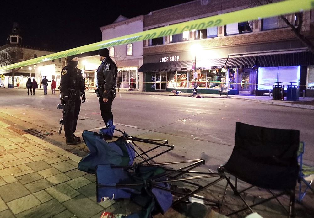 Police stand near toppled chairs lining W. Main St. in downtown Waukesha, Wis., after an SUV drove into a parade of Christmas marchers, Sunday, Nov. 21, 2021. (John Hart/Wisconsin State Journal via AP)
