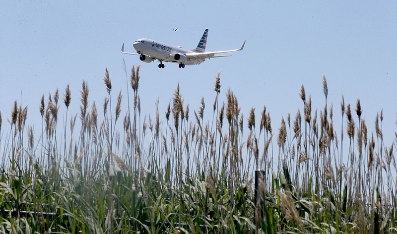 An American Airlines plane flies over fields near O'Hare International Airport on June 16, 2021, in Chicago. Public health officials are urging people to take precautions as the risk of coronavirus transmission is still a possibility — especially for those who are unvaccinated. (Antonio Perez/Chicago Tribune/TNS)