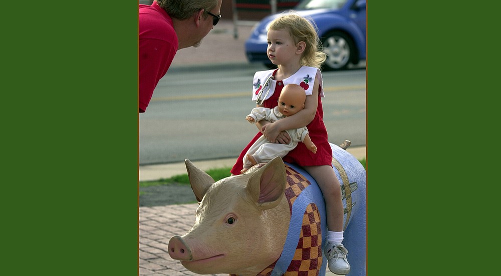 Bob Pearcy talks to his daughter Isabella, while the 2-year-old pretends to ride the Junior League of Little Rock’s Pig on Safari outside the Little Rock Regional Chamber of Commerce on Sept. 5, 2002. (Democrat-Gazette file photo)