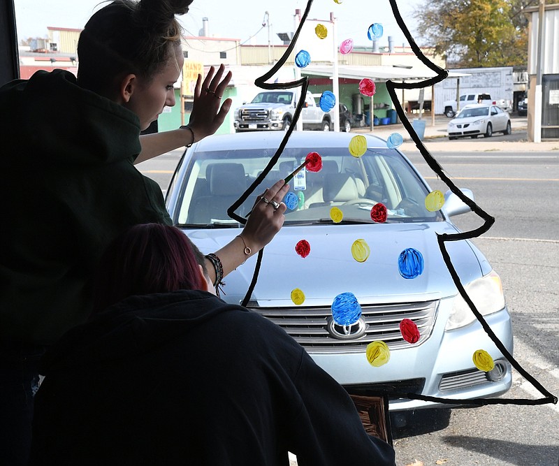 The Sentinel-Record/Tanner Newton /caption: Samantha Jaeger, left, and Kira Dozier, both of Lakeside High School, paint a Christmas tree on the window of Humane Society's thrift store window. HS ChristmasHumane-5 112021.JPG attached