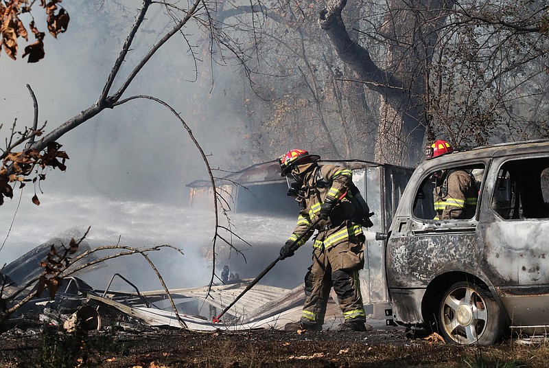 Members of the 70 West and Piney fire departments work to put out a fire at 1636 Caddo Gap Road on Tuesday. - Photo by Richard Rasmussen of The Sentinel-Record