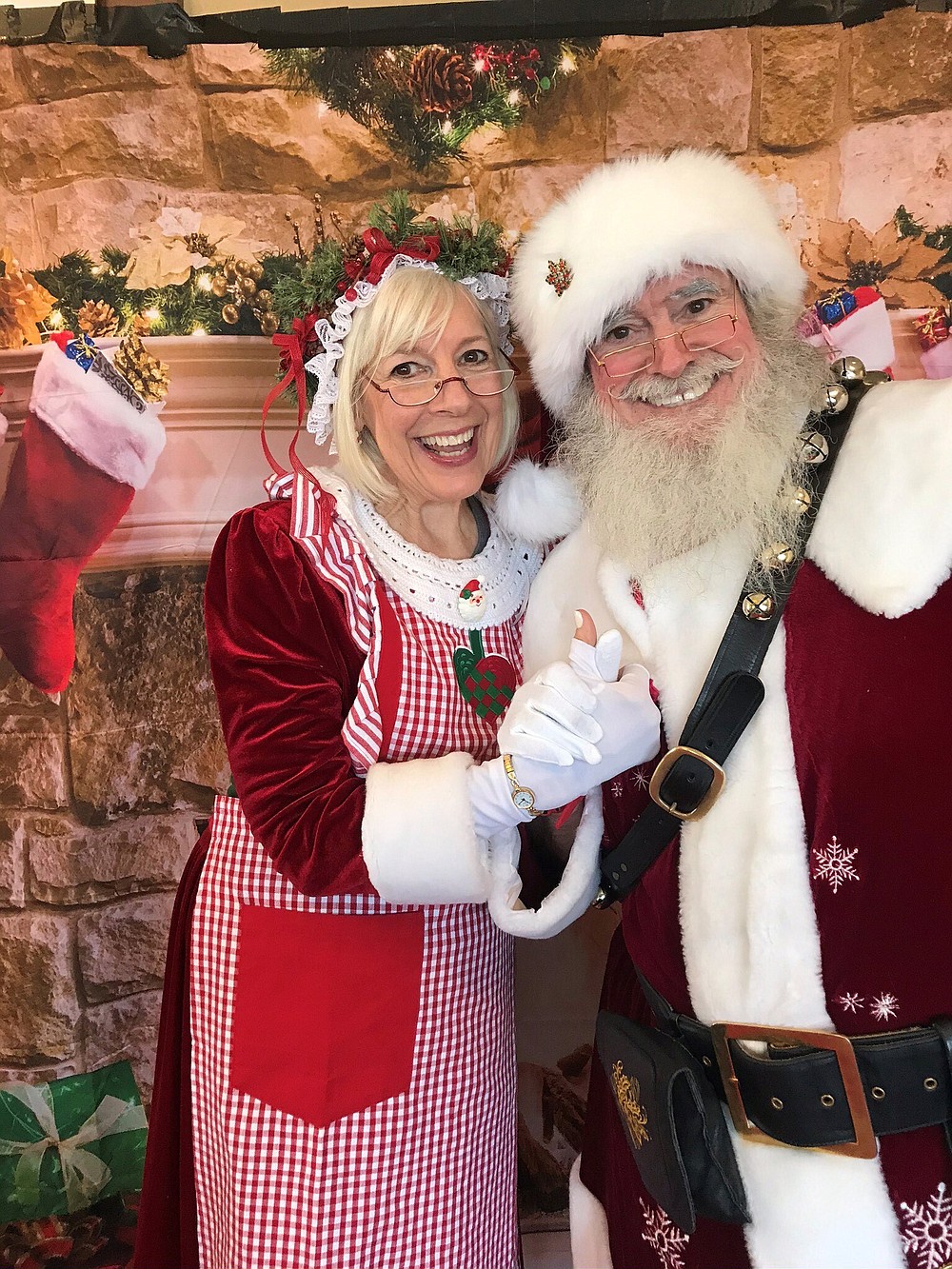 This photo provided by William Hoglund, shows Bill and Laura Hoglund in their Westchester, Ill., living room on Dec. 15, 2019. This will be their eighth year appearing as Santa and Mrs. Claus. The two will mask up as they make their rounds this year. (William Hoglund via AP).
